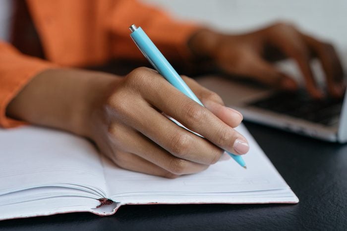 Close Up Shot Of Student Hand Holding Pen And Writing In Notebook, Working At Home. E Learning