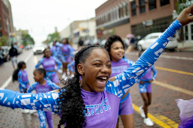 Lexi Watson, 10, of Flint, smiles as she shouts out with joy with Amethyst, an elite dance company, while marching in one of two Juneteenth parades along Saginaw Street in downtown Flint, Mich. on June 19, 2021.