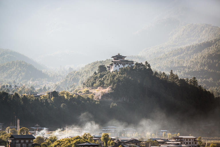 The monastery in Bumthang during the sunset with smoke, forest and magical light.