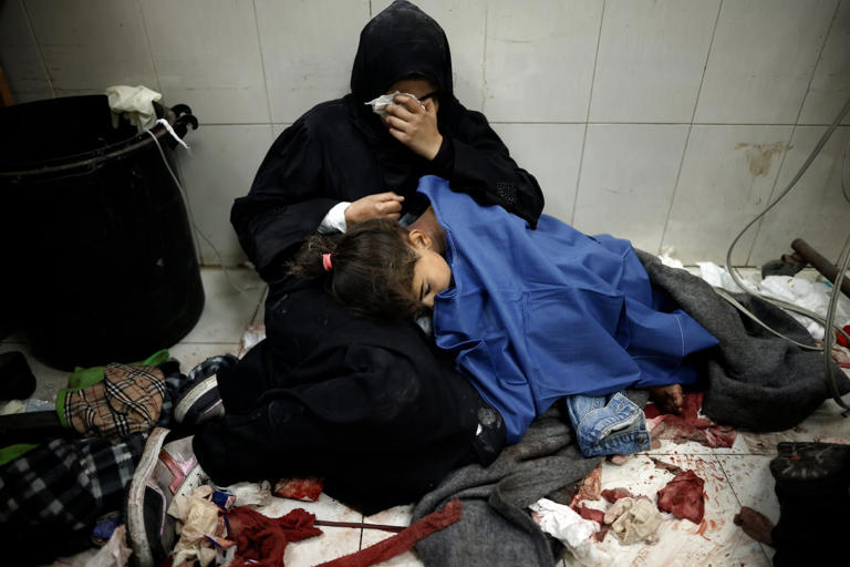 A Palestinian woman cries as she sits next to her girl wounded in the Israeli bombardment of the Gaza Strip while receiving treatment at the Nasser hospital in Khan Younis, Southern Gaza Strip, on Monday, Jan. 22, 2024. (Mohammed Dahman/Associated Press)