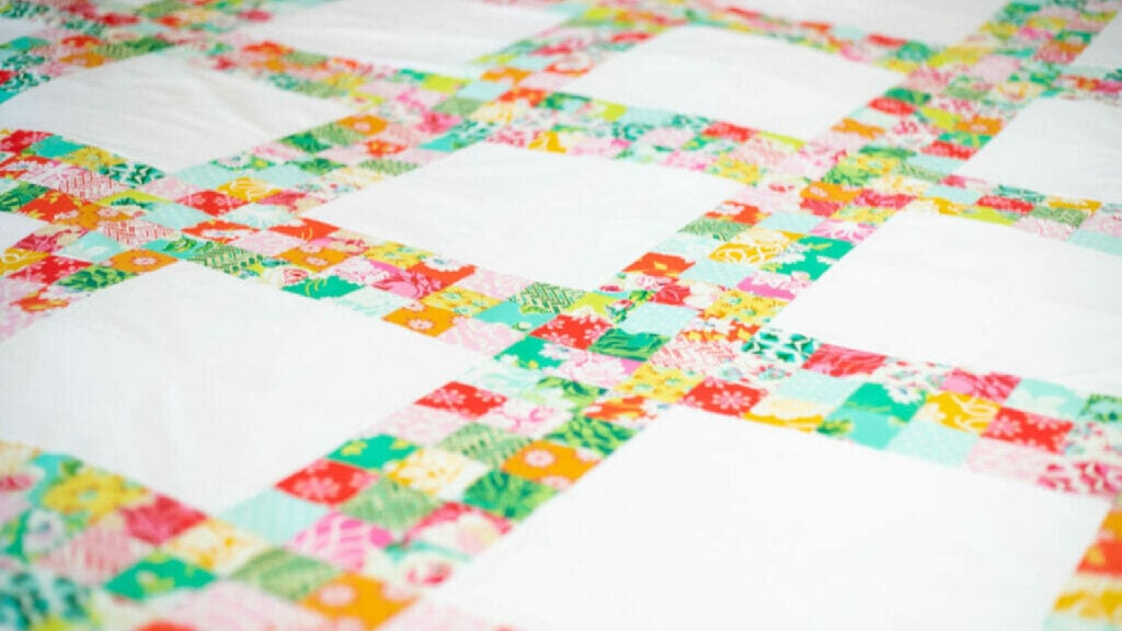 <p>The free <a href="https://sewcanshe.com/grandmas-lattice-quilt-free-pattern/" rel="noreferrer noopener">Grandma’s Lattice Quilt Pattern</a> uses strip piecing and a jelly roll bundle to sew this gorgeous lattice-style quilt! This quilt piecing technique is so much faster than cutting 2 1/2” squares and sewing them together (which is fun, too – I did that for this super scrappy <a href="https://sewcanshe.com/how-to-sew-an-easy-patchwork-quilt-using-2-1-2-fabric-squares/" rel="noreferrer noopener">patchwork quilt</a>). I used True Kisses fabric from Heather Bailey. </p>