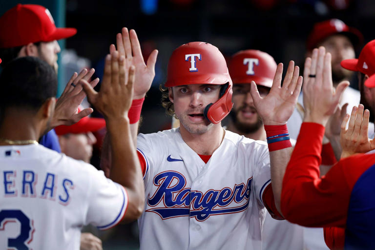 Texas Rangers DJ Peters is congratulated by teammates after scoring on Brock Holt's go-ahead two RBI double during the eighth inning against the Los Angeles Angels at Globe Life Field in Arlington, Texas, Thursday, September 30, 2021.