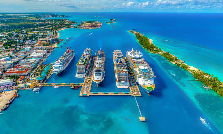 Learn more about the Nassau cruise port which is a popular travel site. Pictured: Nassau, Bahamas’ cruise port with bright blue waters and lush green trees.