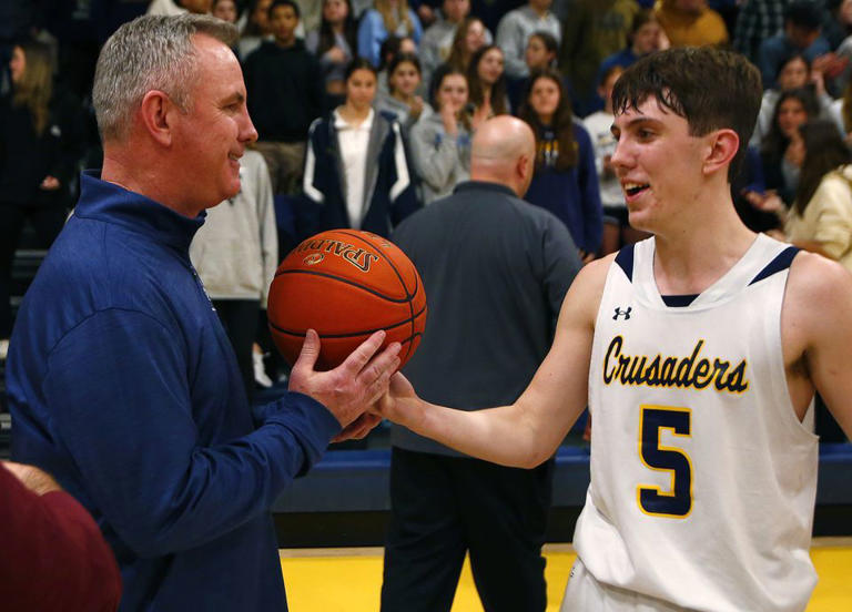 Notre Dame coach Pat Boyle takes the game ball from his son, Colin, after beating Bangor for his 500th career victory on Jan. 26, 2024.