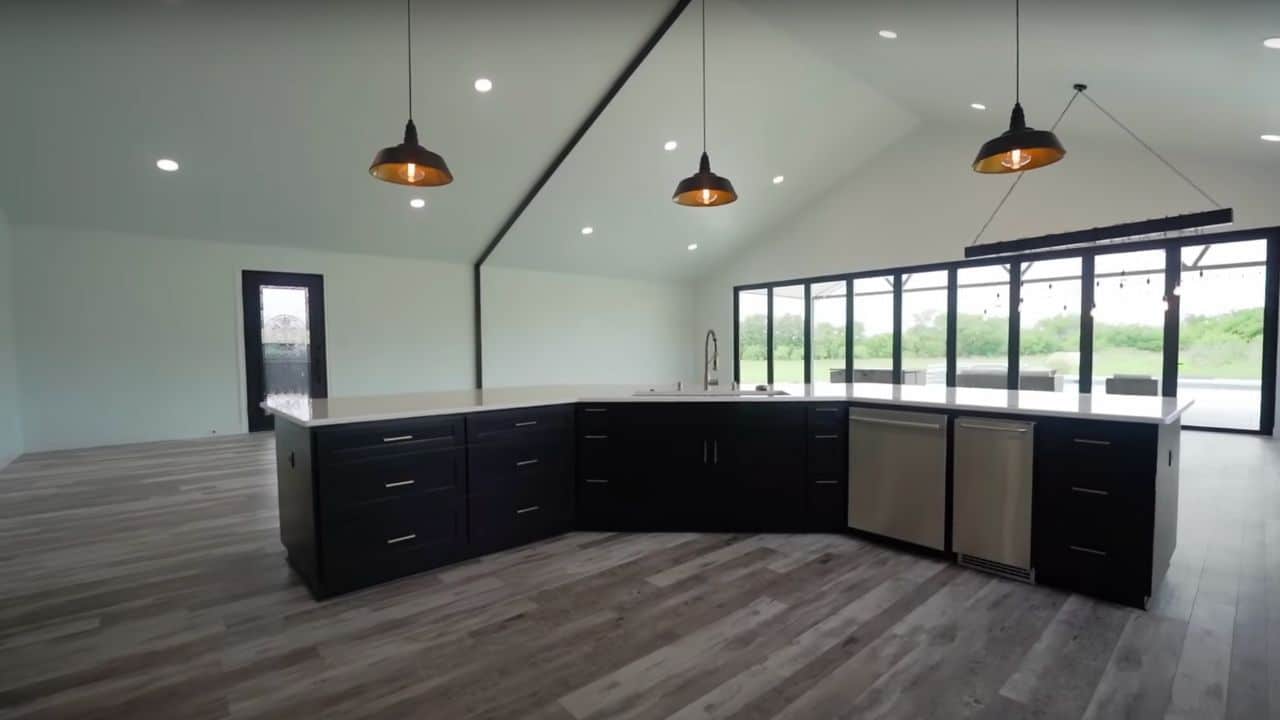 <p>The kitchen has a contemporary, modern feel with a black-and-white color scheme. The island and cabinetry are painted black, contrasting with the white walls.</p>