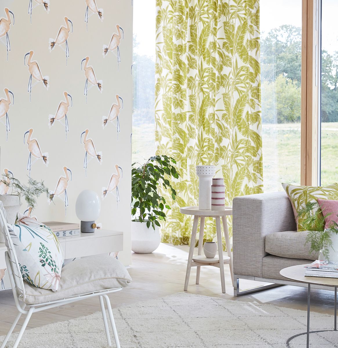 <p>Another clever living room wallpaper idea is to use it as a partition. In a through room, use wallpaper to define the spaces. This fun but sophisticated flamingo design gives the room a Miami feel, further complemented by the retro-style palm leaf fabric on the <a href="https://www.housebeautiful.com/uk/decorate/windows/g35224529/best-blackout-curtains/">curtains</a> and the white metal pool chair.</p><p><em>Pictured: Zanzibar wallpaper; Parlour Palm Citrus Fabric, both <a href="https://scion.sandersondesigngroup.com/">Scion</a></em></p>