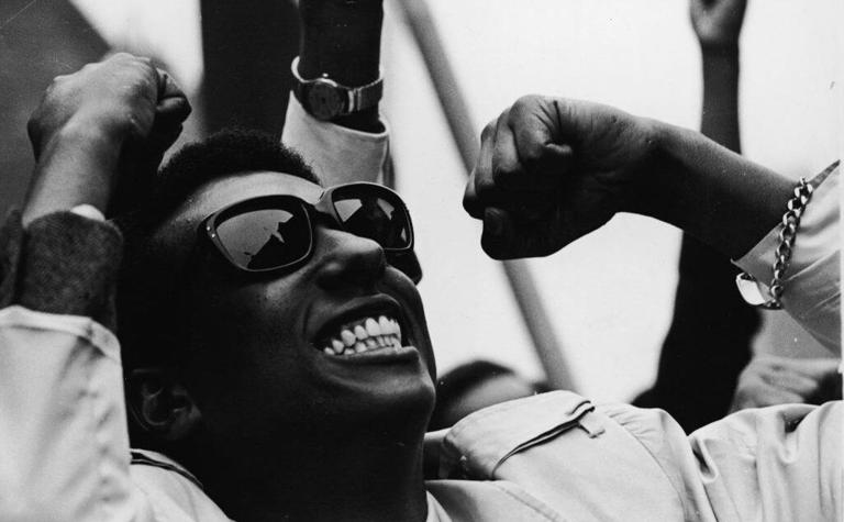 Hear are some important Black History Speeches. Pictured: a Black and white image of Stokely Carmichael cheering. | Dwayne Bey/Getty Images