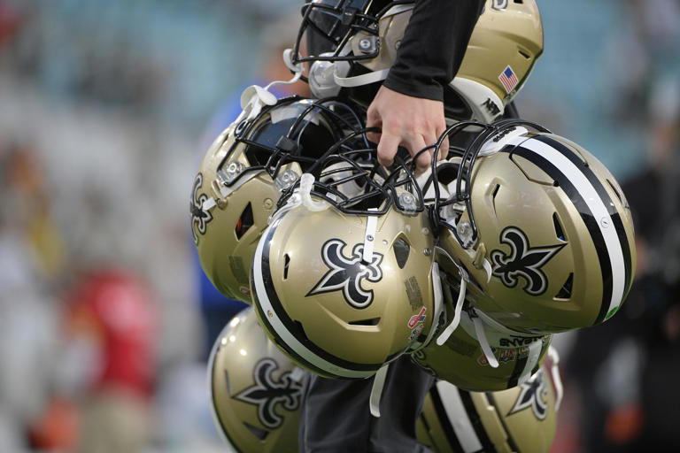 Equipment staff leaves the field with New Orleans Saints helmets after an NFL football game against the Green Bay Packers, Sunday, Sept. 12, 2021, in Jacksonville, Fla. (AP Photo/Phelan M. Ebenhack)