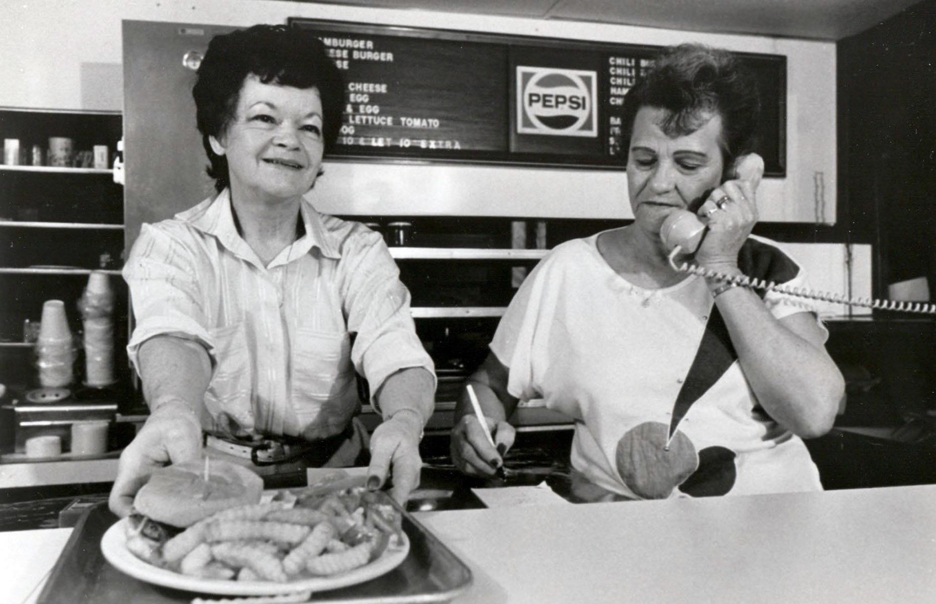 <p>A major part of the Goody Goody story, Yvonne Freeman (pictured here, left) started out as a carhop for Goody Goody from 1947-49. After a 10-year hiatus, while she had her five sons, she returned as waiting staff in 1959. Yvonne took exclusive responsibility for making the Goody Goody burger's secret sauce, a recipe handed down unchanged from the Stephens years. She also made the delicious homemade pies herself. From 1985 to 2005, Freeman was manager of Goody Goody, although was better known as 'the queen of hamburgers'. </p>