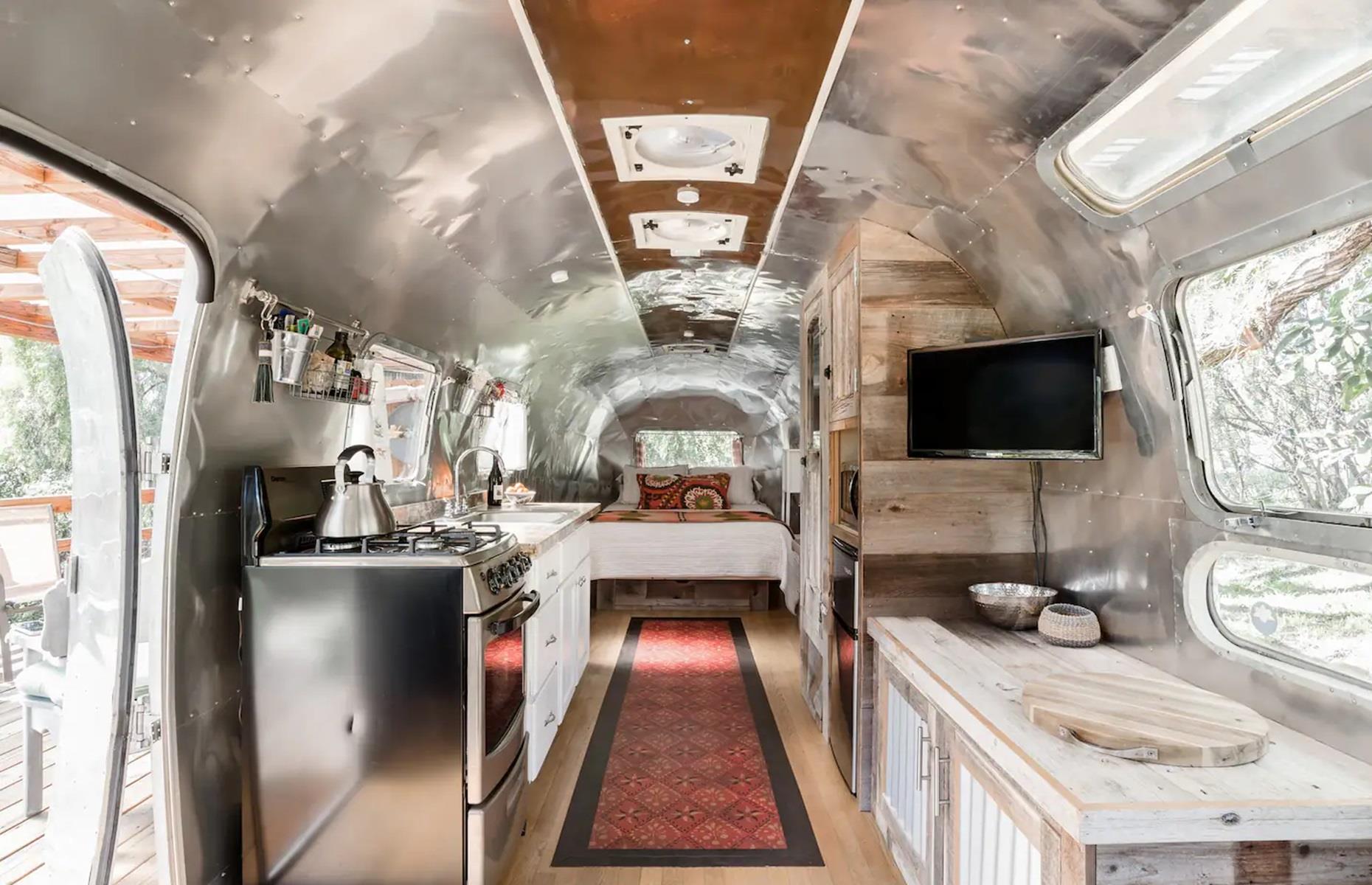 <p>Delia wanted her guests to be able to climb out on either side, so had to have the bed created to fit the Airstream's measurements. The space is lit by a vintage wall sconce, while the closet was made from a 100-year-old piece of wood from Connecticut, which Delia's friend donated to her.</p>  <p>Outside, there's a covered deck, where people can relax and soak up the stars, as well as an amazing outdoor bathroom formed from timber, corrugated aluminum and plumbing parts.</p>