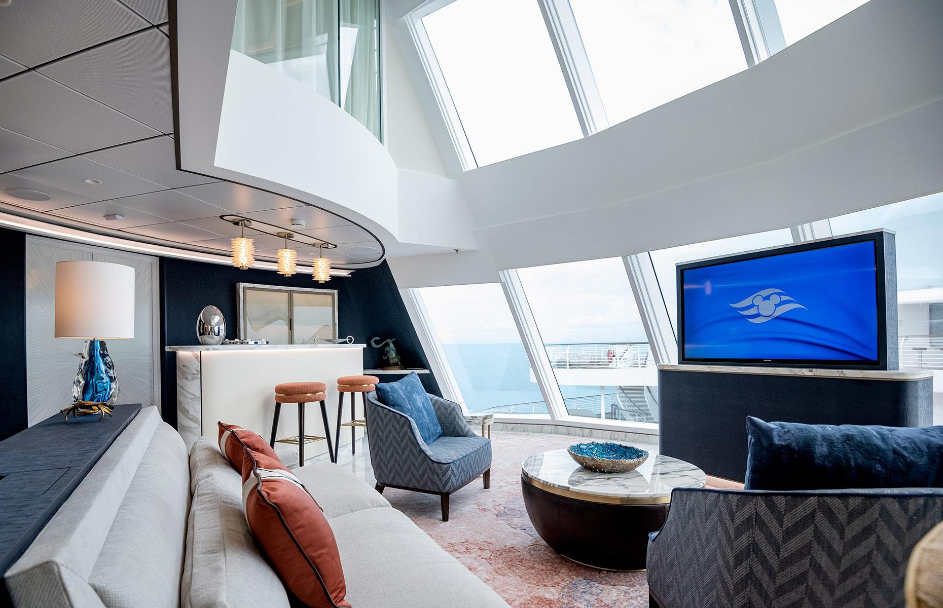 <p>Perched in the funnel of the ship, high above the upper decks, the Tower Suite is accessed by its own private elevator. Inside, the two-story living room features a chandelier, floor-to-ceiling glass windows and decor subtly inspired by the Disney movie <em>Moana</em>. A grand spiral staircase connects the palatial living area, which includes a dining salon and wet bar, to the suite's four bedrooms. Added perks include a concierge who handles your priority reservations, and access to a VIP lounge and sun deck.</p>