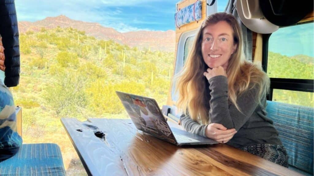 <p>Some van lifers opt for a convertible dinette that folds down into a bed at night. This setup has its pros and cons: it provides a large workstation, but you have to make your bed every morning and every night. Here, writer Sierra Eberly is enjoying a desert view while working on her projects.</p>