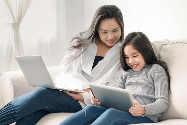 happy mother and daughter with laptop and tablet pc