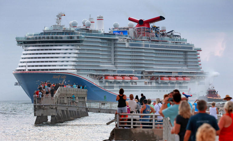 At dawn, fans line up at Jetty Park to see the Carnival Cruise Line ship Mardi Gras arrive at Port Canaveral, Florida, on June 4, 2021.