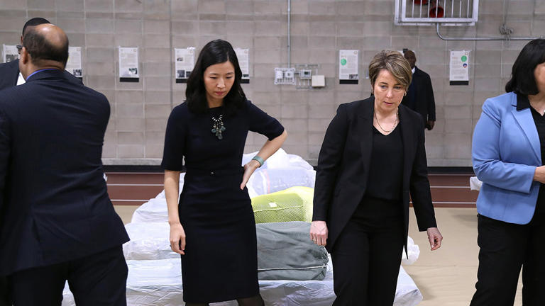 Boston Mayor Michelle Wu, center left, and Massachusetts Governor Maura Healey pause to look at the cots set up on the gym floor as state and local officials toured the Melnea A. Cass Recreational Complex. John Tlumacki/The Boston Globe via Getty Images