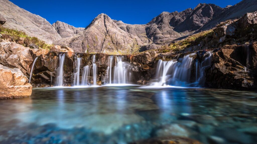 <p><span>One of the most unique places on the Isle of Skye, the Fairy Pools are gorgeous. It is found in Glenbrittle and has several crystal-clear water pools that flow from the Cuillin Mountains.</span></p><p><span>You have to pay for parking, but other than that, the site is free to visit. It’s a 15-20 minute walk to reach the first set of pools. If you’re brave enough, you can jump in for a swim, but be careful, as the waters can be frigid.</span></p>