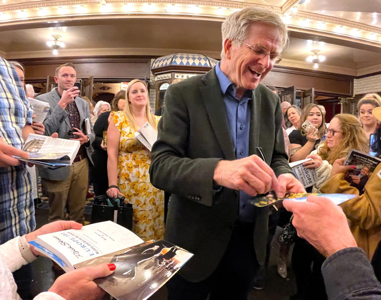 Travel personality Rick Steves autographs books and programs beneath the marquee of Abilene's Paramount Theatre after his show there Tuesday.