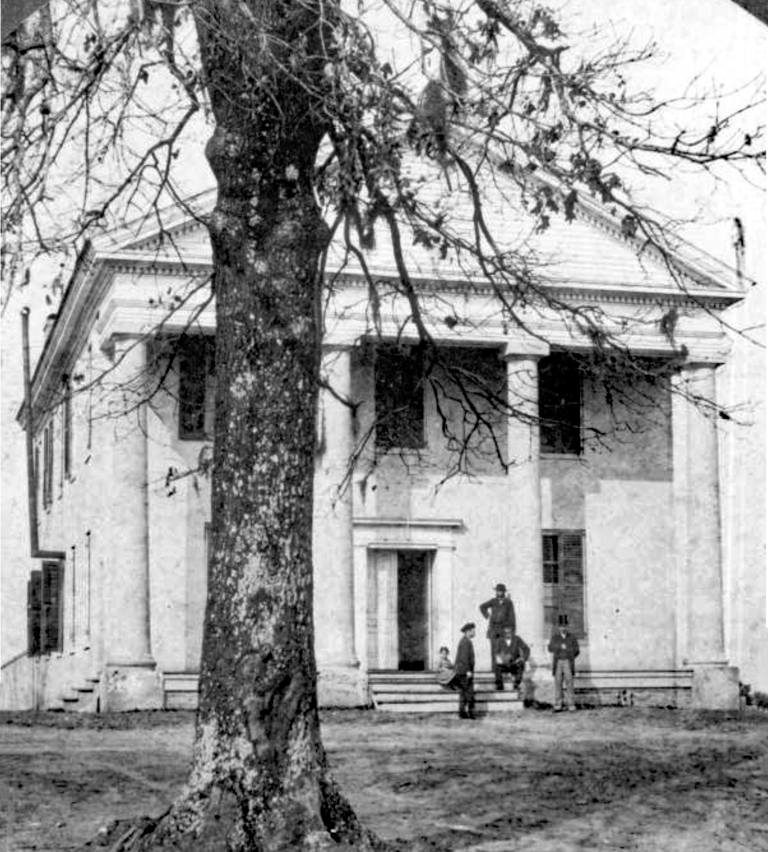 A group stands on the steps of the first building at the West Florida Seminary in the 1880s.
