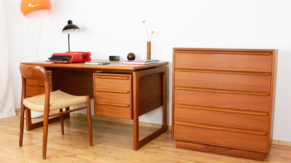 woman repairs stained solid wood mid-century modern desk to original glory