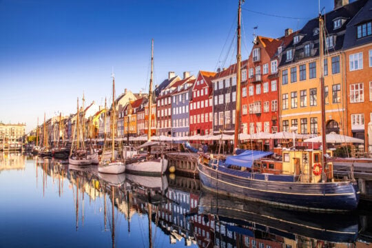 <p><span>Denmark, the land of Vikings, is a Scandinavian wonder famed for its high quality of life. Known for its commitment to sustainability, Denmark is one of the world leaders in wind energy and cycling culture.</span></p><p><span>The Danish concept of ‘hygge’, which represents comfort and contentment, permeates every aspect of life here. From the colorful waterfront of Nyhavn to the historic castles and modernist architecture, there’s a wealth of sights to explore.</span></p><p><span>And let’s not forget Danish pastries! Denmark embodies the essence of ‘ happy living ‘ with a strong emphasis on work-life balance, excellent healthcare, and a safe living environment.</span></p>