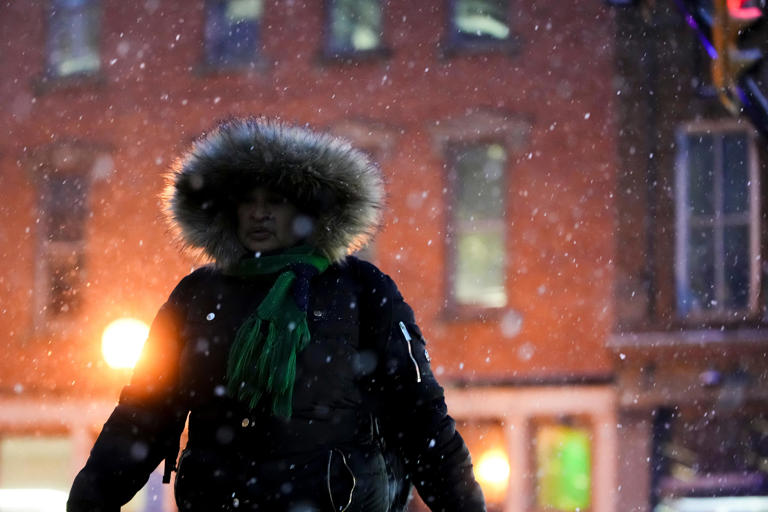 Pedestrians walk through the steady snowfall Friday night in downtown Columbus.