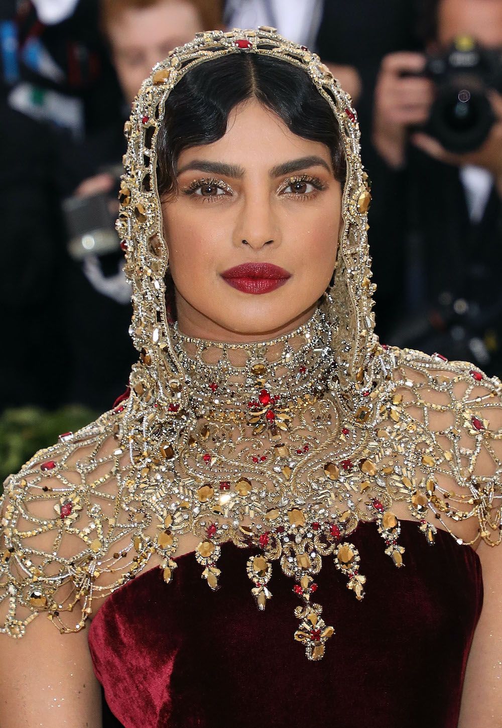 <p>                     We love it when the make-up pulls together an outfit, and Priyanka Chopra’s gold eyeshadow and dark red lip perfectly matched hers at the 2018 event—which had one of the most memorable Met Gala themes, “Heavenly Bodies: Fashion and the Catholic Imagination”.                   </p>
