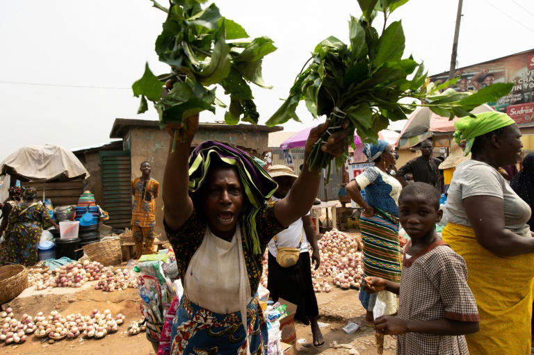 Une femme brandit des légumes lors d'une manifestation contre la vie chère à Ibadan, au Nigeria, le 19 février 2024