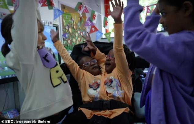 touching moment conjoined twins marieme and ndeye are given their own coats at inclusive design facility after their dad struggled to find them clothes - as seven-year-olds who were given days to live defy the odds
