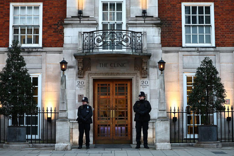 Police officers stand guard outside the London Clinic, where Princess Kate was hospitalized for a “planned abdominal surgery.”