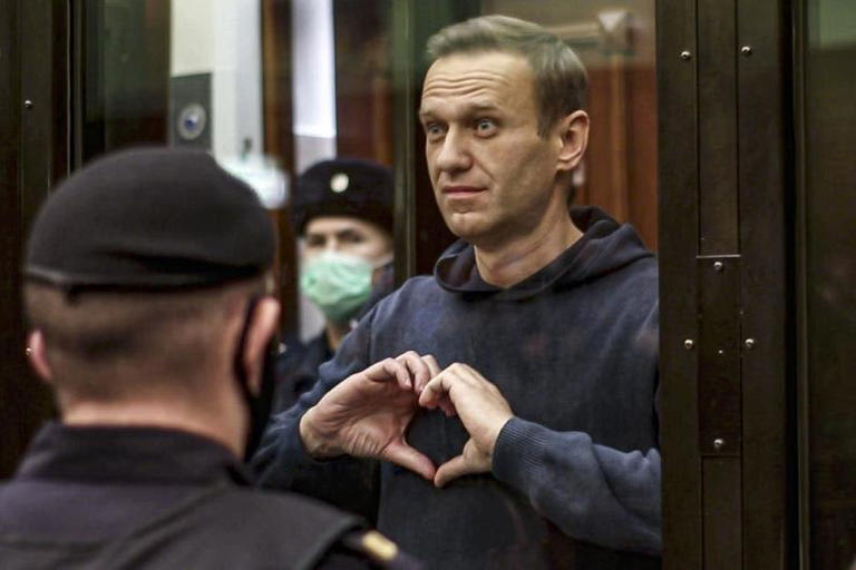 In this handout photo taken from video, provided on Feb. 2, 2021, Russian opposition leader Alexei Navalny makes a heart sign while standing in a defendants cage during a hearing in the Moscow City Court in Moscow. ©Moscow City Court via AP, File