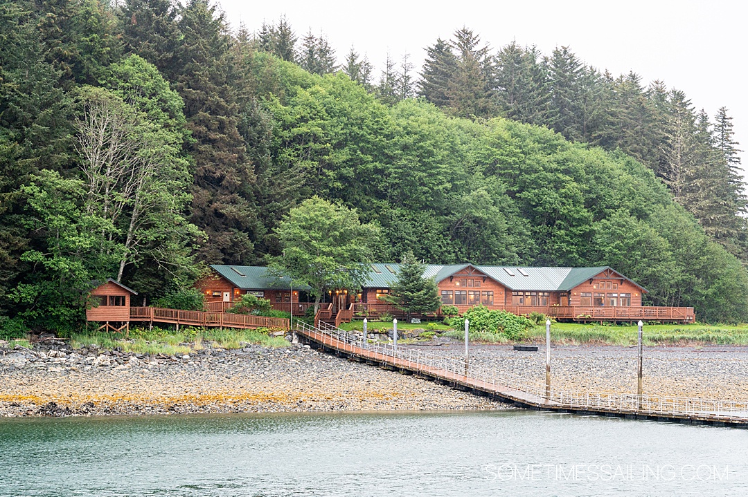 Wooden building in the distance on an island in Alaska. It is Orca Point Lodge, a structure owned by Alaskan Dream Cruises.