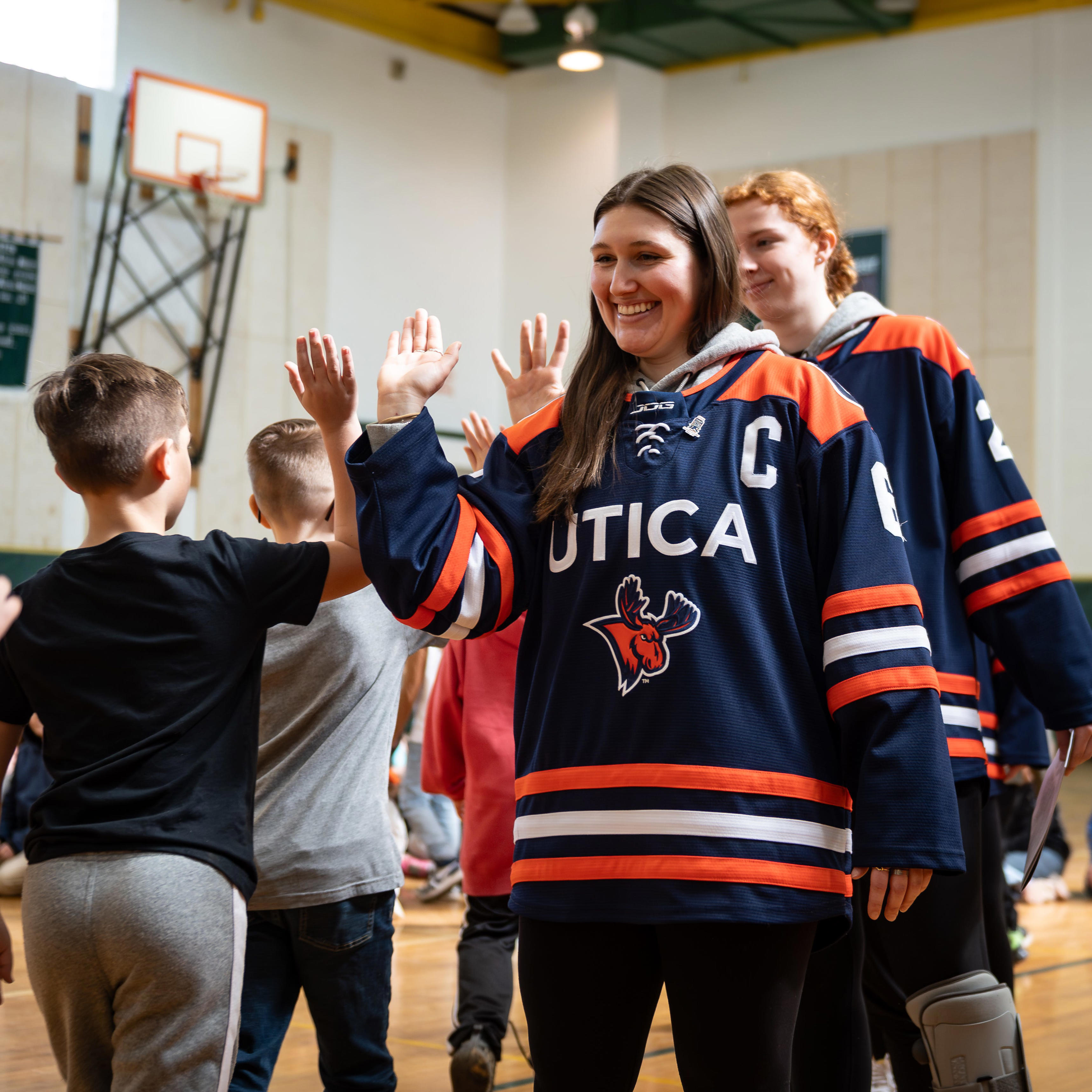 Utica University women's hockey players hand out IIHF activity books to