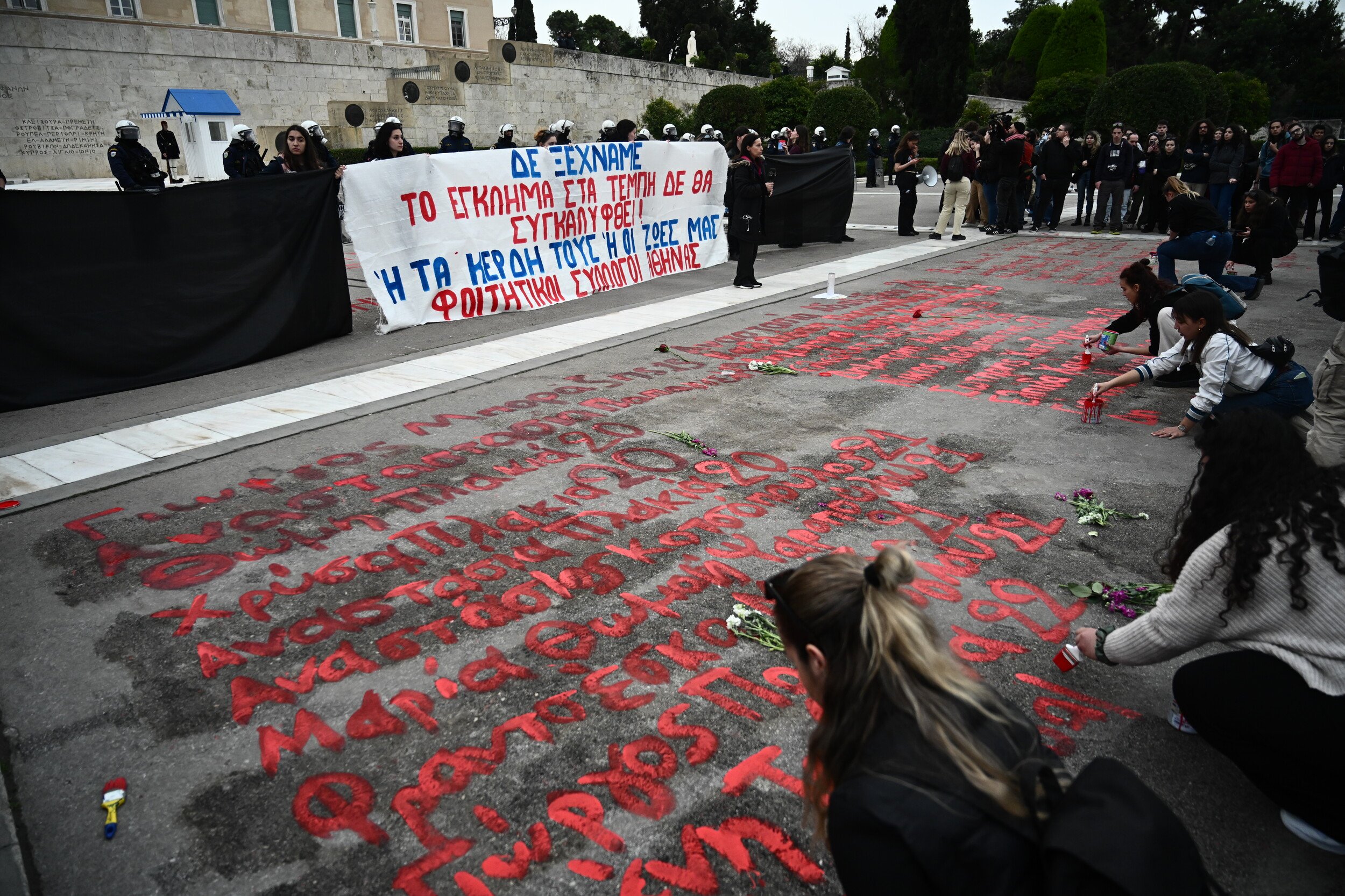 τέμπη: φοιτητές ξαναγράφουν τα ονόματα των 57 νεκρών που σβήστηκαν έξω από τη βουλή