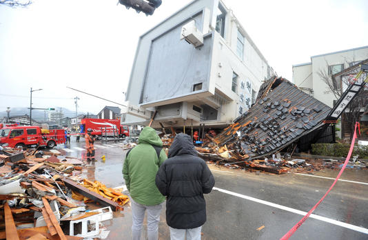 【大きな揺れ】震度７の揺れで倒壊した石川県輪島市内の７階建てのビル。隣接する家屋も甚大な被害が