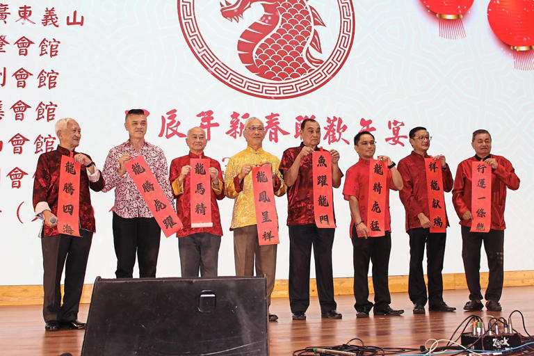 Unfurling blessings written as calligraphy are Lee (far left) and representatives from Chinese associations.