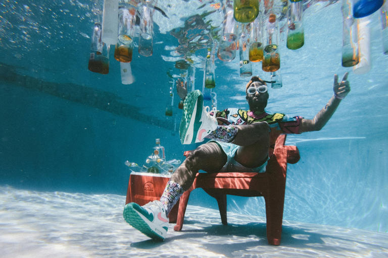 man posing in chair with bottles under water
