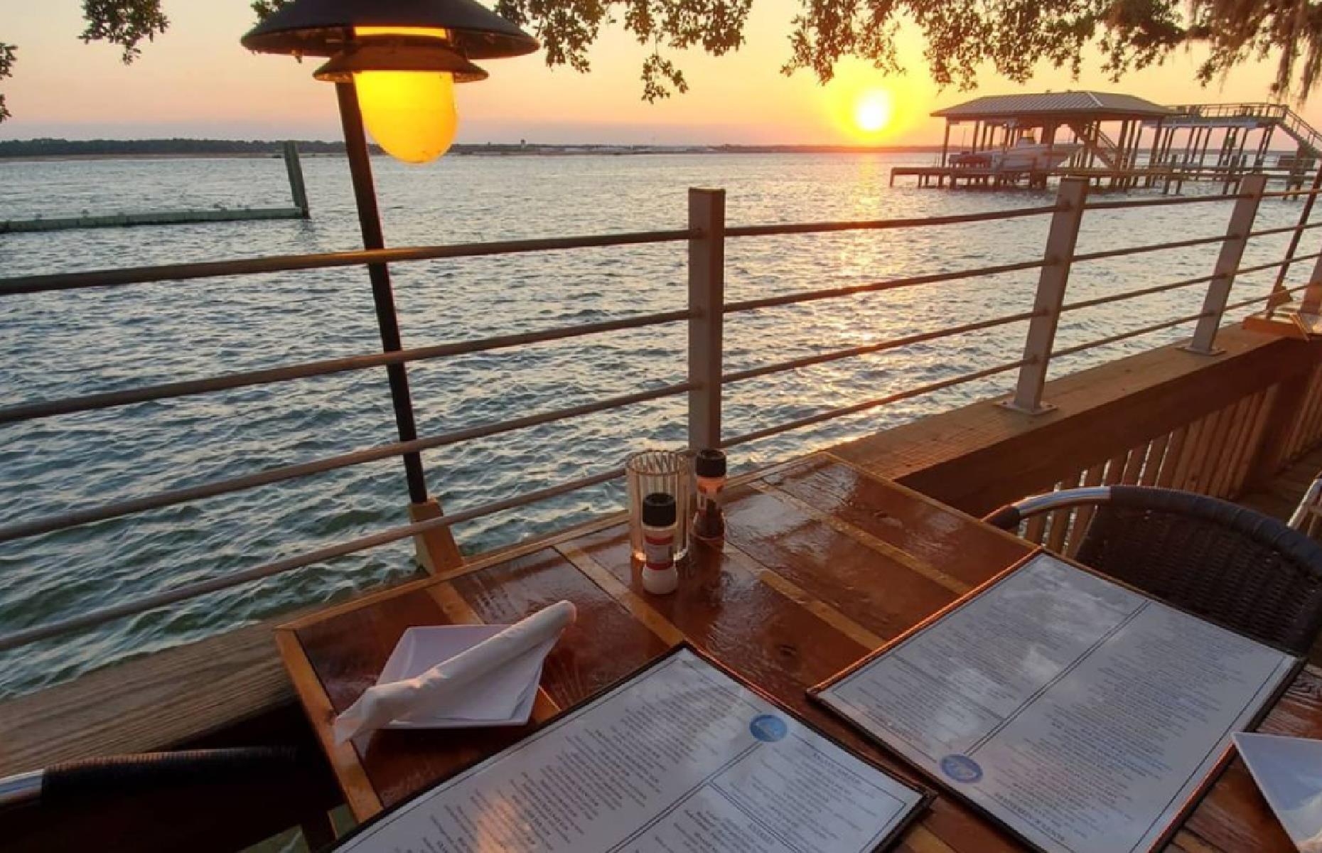 <p>There are few more special spots for watching the sun go down than Cap’s on the Water, which has tables scattered around the huge outdoor deck and jetty by the Intracoastal Waterway. Trees provide shade and make the restaurant, which specializes in seafood with Southern and Mediterranean flavors, look even lovelier. The indoor areas haven’t been neglected, though, with raffia booths and plush sofa-style seating, gorgeous light fittings and wall lamps, and windows that can be thrust open to allow the balmy breeze in on warm nights.</p>