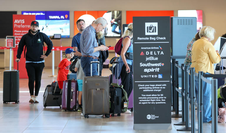 Airline passengers check bags at a remote bag check near an Avis car rental kiosk on March 5 at Tampa International Airport. The airport saw a record number of passengers Sunday amid widespread delays and cancellations caused by inclement weather.
