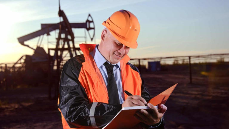 An oil worker assesses productivity at an oil rig as ASX 200 energy shares continue to rise.