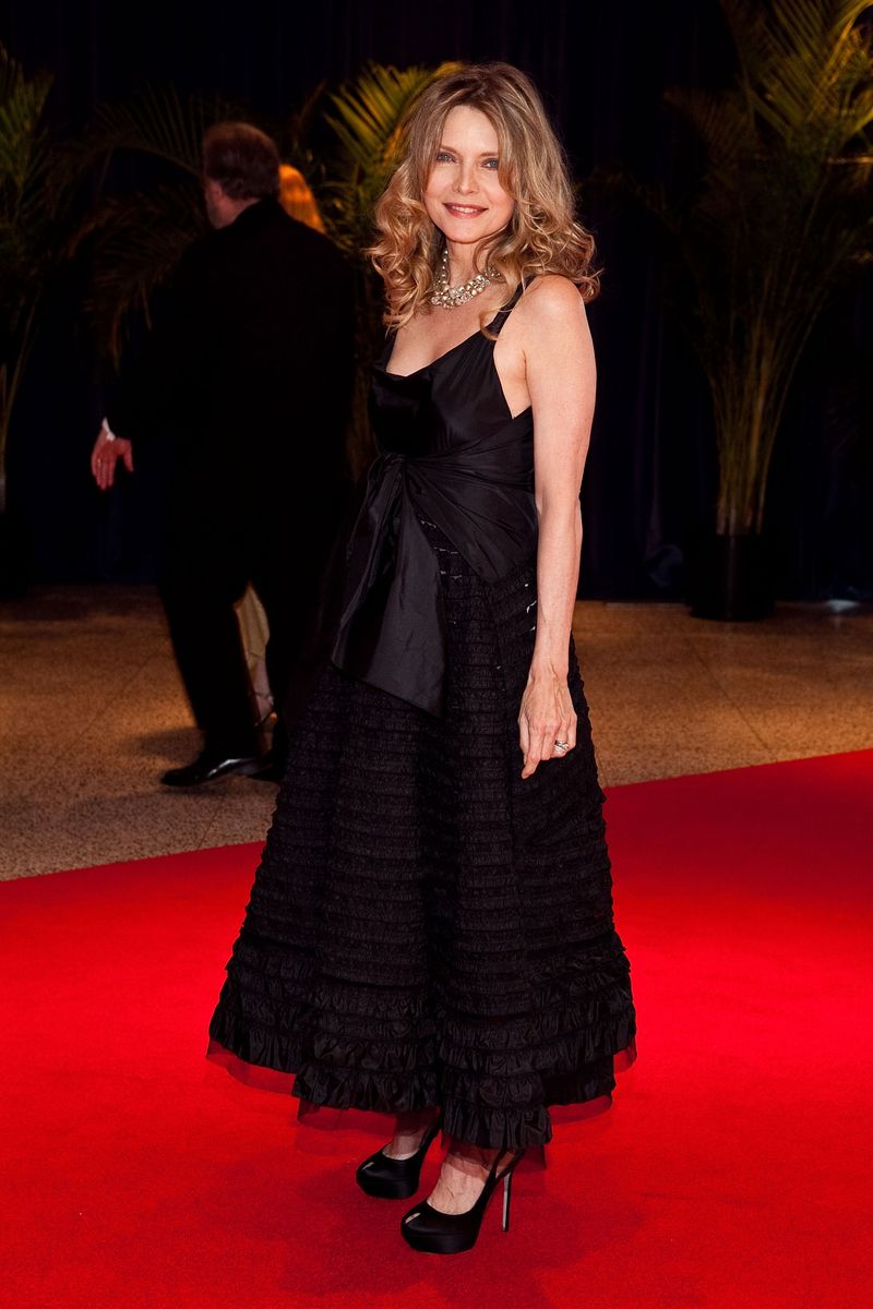 <p>Pfeiffer posed on the red carpet in a flouncy black dress with a ruffled hem and oversized front center bow. She styled the look with sky-high platform heels and a layered pearl necklace.</p>