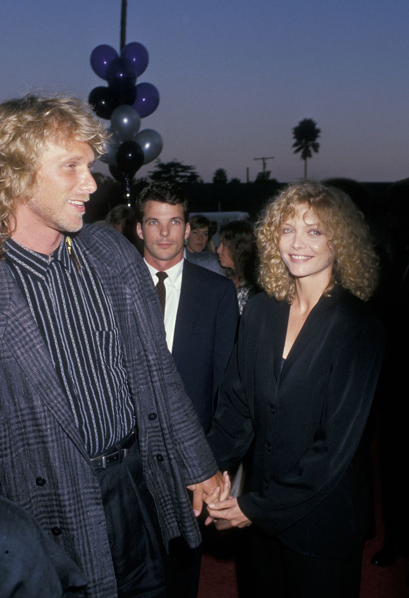 <p>Pfeiffer held hands with her then-husband Peter Horton at the Beverly Hills premiere of <em>Married to the Mob</em>. The actress decided on a cowl-neck black ensemble and a curly hairstyle for the occasion. </p>