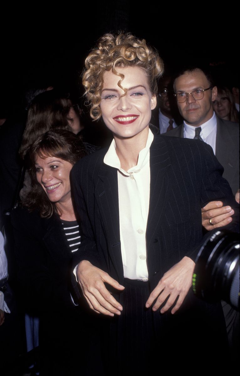 <p>Pfeiffer tossed on one of her tried-and-true classics—a tailored black pantsuit with a crisp white blouse—for the Los Angeles premiere of <em>Frankie and Johnny</em>. She styled the outfit with a statement-making curly updo and eye-catching red lip.</p>