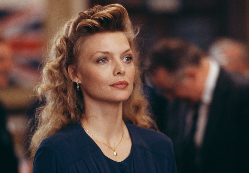 <p>On the set of <em>The Russia House, </em>Pfeiffer wore a navy ensemble accessorized with a simple gold chain necklace and matching earrings. She looked stunning in an uncharacteristic half-up, half-down bouffant hairstyle that tied the look together perfectly. </p>
