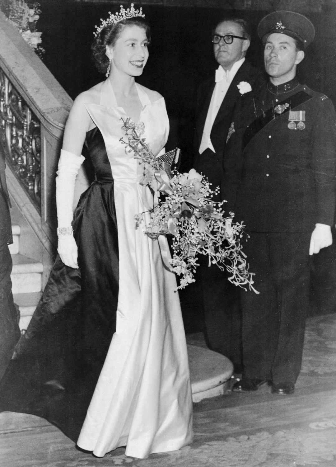 <p>                     This might be perhaps the grandest exit of the theatre we've ever seen. Pictured here leaving the Empire Theatre in Leicester Square after attending the Royal Film Show in 1952, Queen Elizabeth looks an absolute vision in her black and white satin gown. The regal ensemble was of course topped off with 'Granny's tiara', some elongated diamond earrings and a matching bracelet.                   </p>