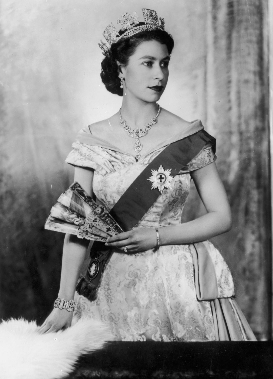 <p>                     A truly iconic image of the late Queen, this black and white studio portrait taken of the young royal in 1955 shows her wearing a regal brocade dress, a red sash with the star of the Order of the Garter attached and of course a breathtaking diamond and pearl tiara atop her head.                   </p>
