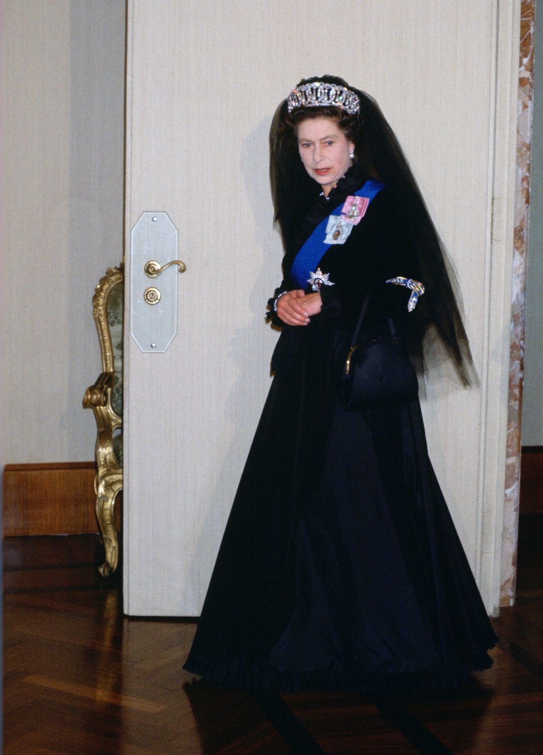 <p>                     Visiting the Vatican calls for an unusual regal ensemble, which is why Queen Elizabeth II is seen here wearing a traditional black full-length dress and matching black veil. She wore the outfit, along with the Grand Duchess Vladimir Tiara during an audience with the Pope in 1980.                   </p>