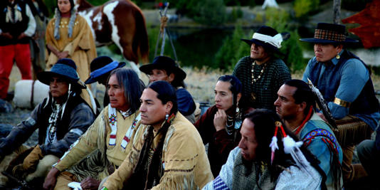 Native Americans listen to someone talking in Outlaw Posse