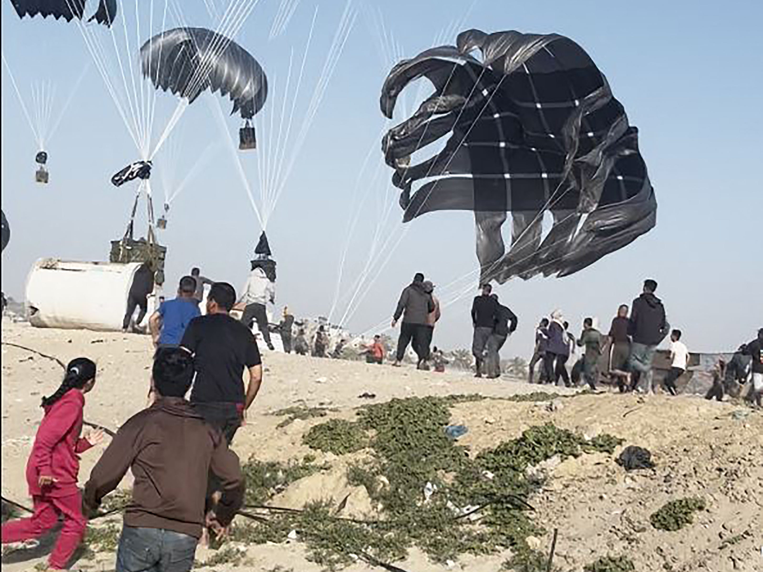 images show palestinians running toward food parcels attached to parachutes as us airdrops begin on gaza beach