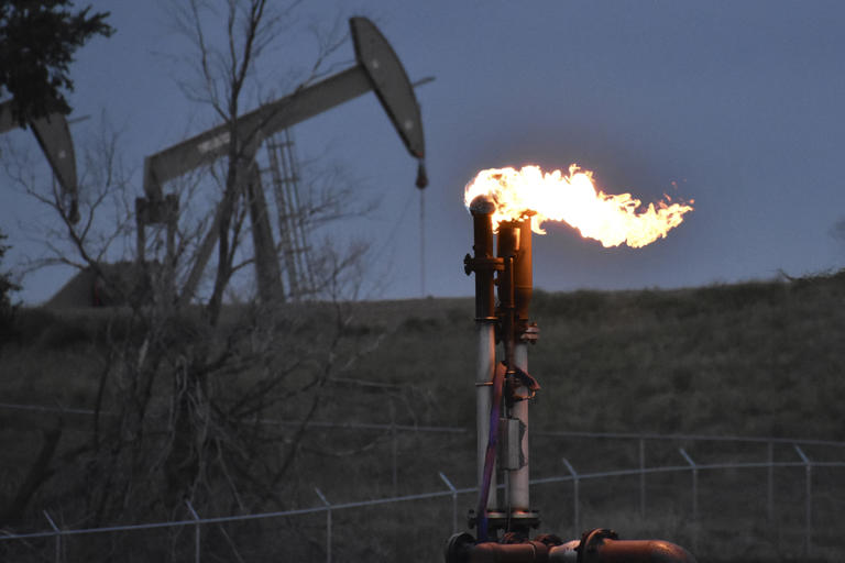 A flare to burn methane from oil production is seen on a well pad near Watford City, North Dakota, Aug. 26, 2021.