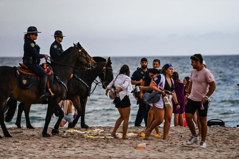 Fort Lauderdale Mounted Police officers escort revelers off the beach on Las Olas Boulevard in Fort Lauderdale, Florida, March 16, 2022. The beach closes at 5:30 p.m. during spring break season, a tactic to control chaos for visiting college students and young adults.